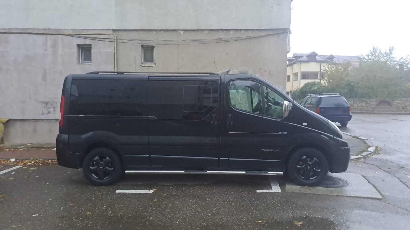 Duba neagră Renault Trafic Passenger a CCC Transport, văzută din profil, cu treptele laterale