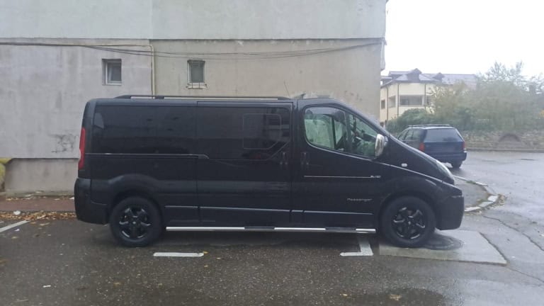 Duba neagră Renault Trafic Passenger a CCC Transport, văzută din profil, cu treptele laterale